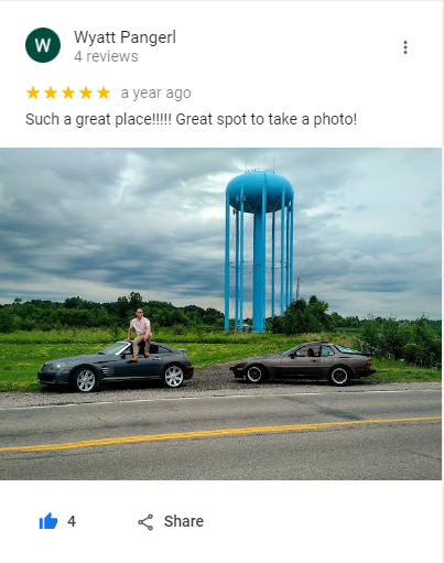 Screenshot of the review by Wyatt Pangerl, with a picture of a man sitting on the top of a car by the road next to the water tower.