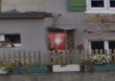 Zoomed in picture of the Swiss flag hung off the eave of a house on the left