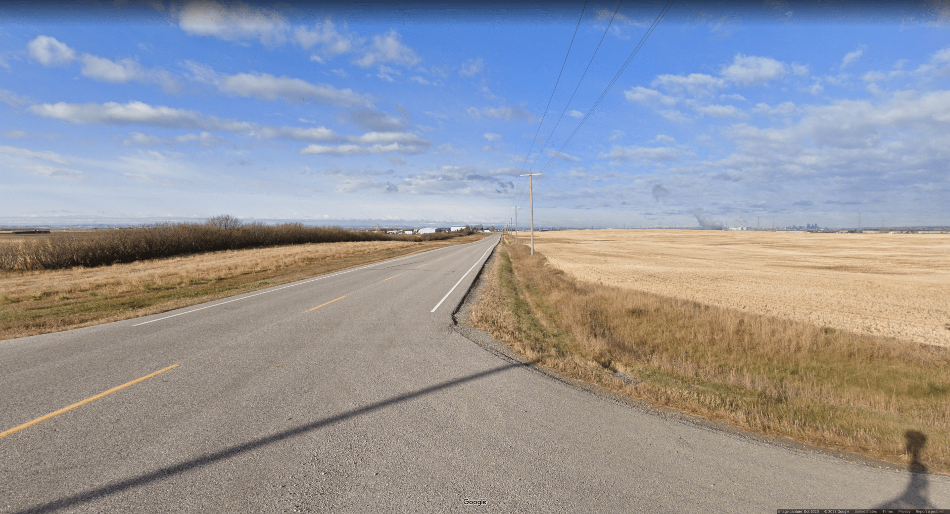 Picture of a paved road spanning an extremely flat area covered with dead prairie grass