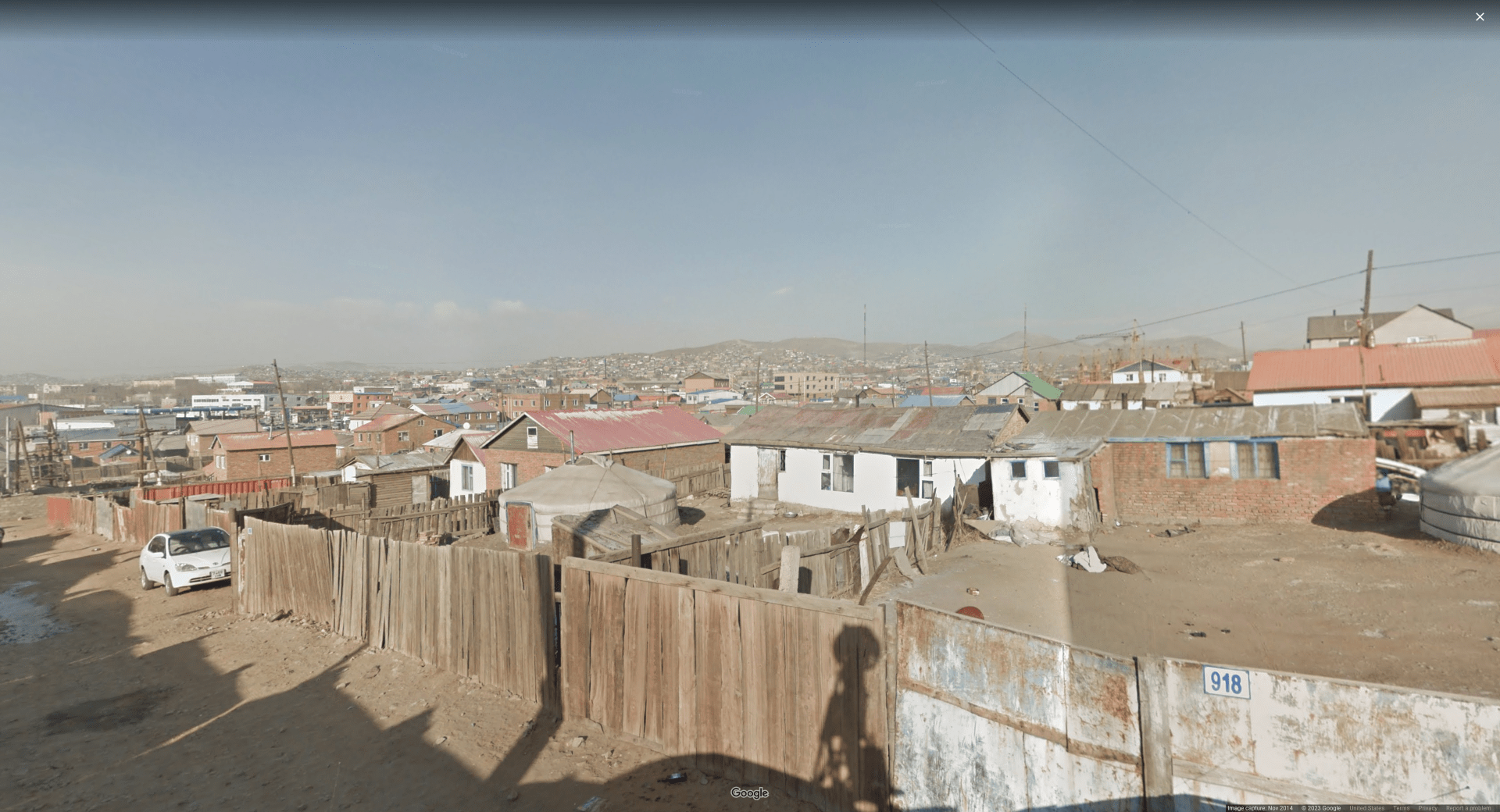Picture of a giant neighborhood in a brushland/desert region, with wooden fences, roofs, and electric poles